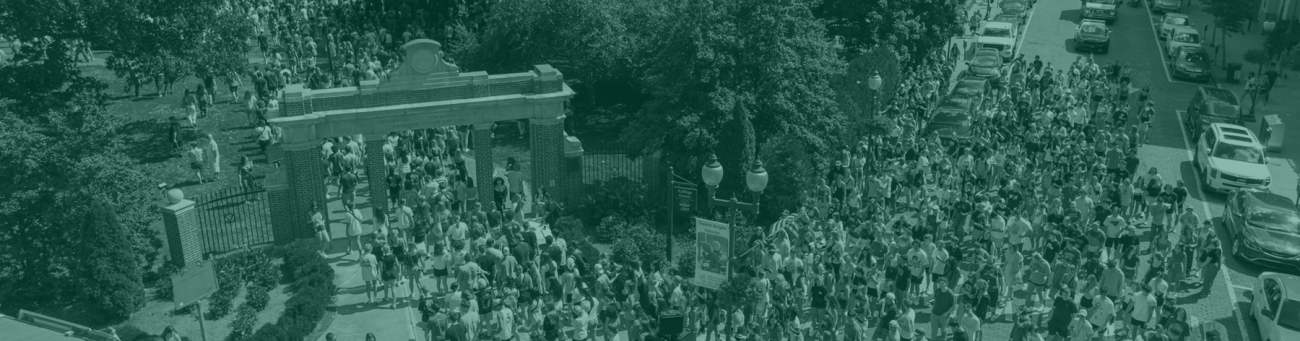 a large group of students walking through the Alumni Gateway on College Green